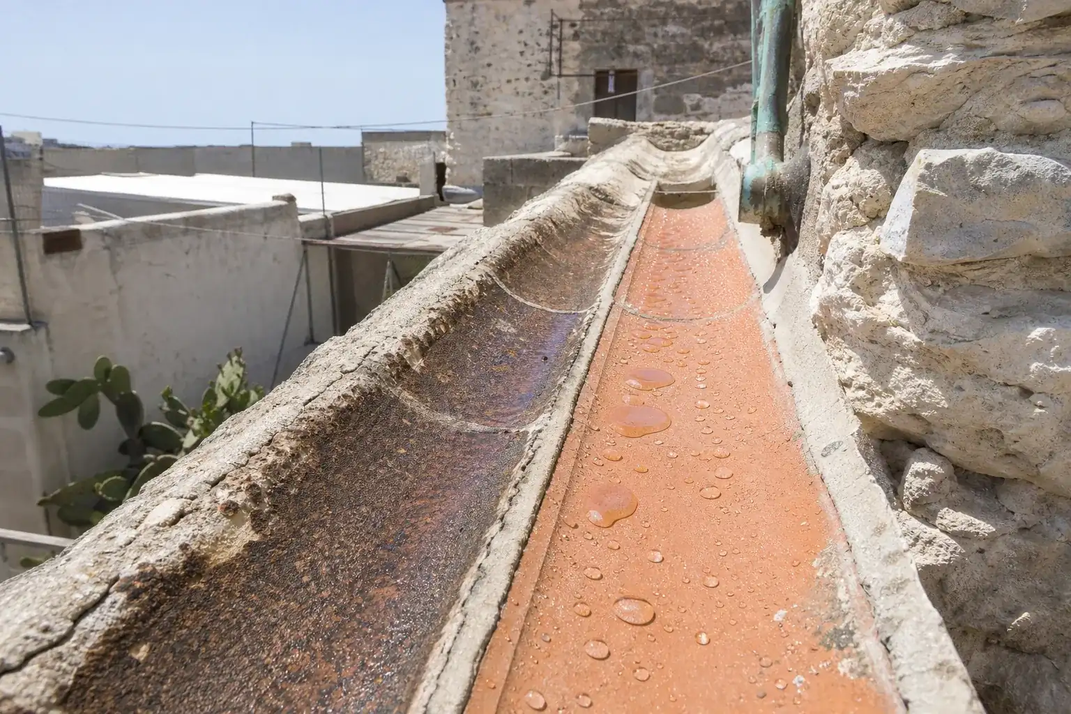 Gouttes d’eau perlant sur une tuile canal traitée, la tuile voisine non traitée ayant foncé sous l’humidité