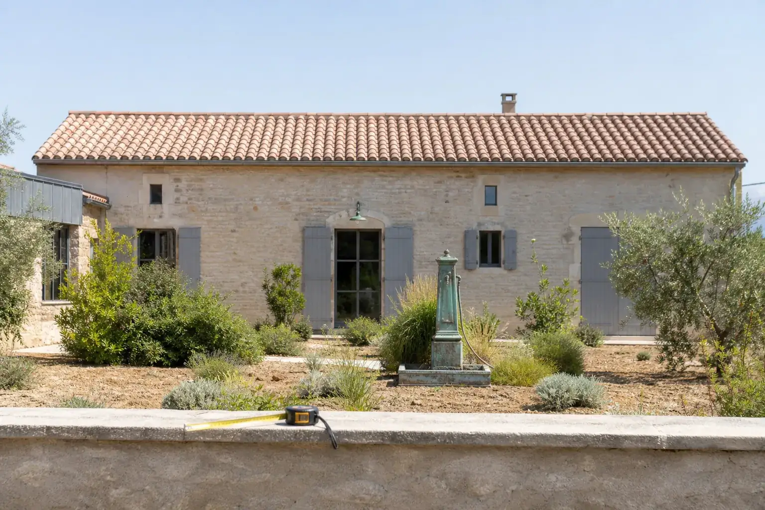 Maison méditerranéenne vue de face depuis le jardin, toiture de tuile canal visible d’un bout à l’autre