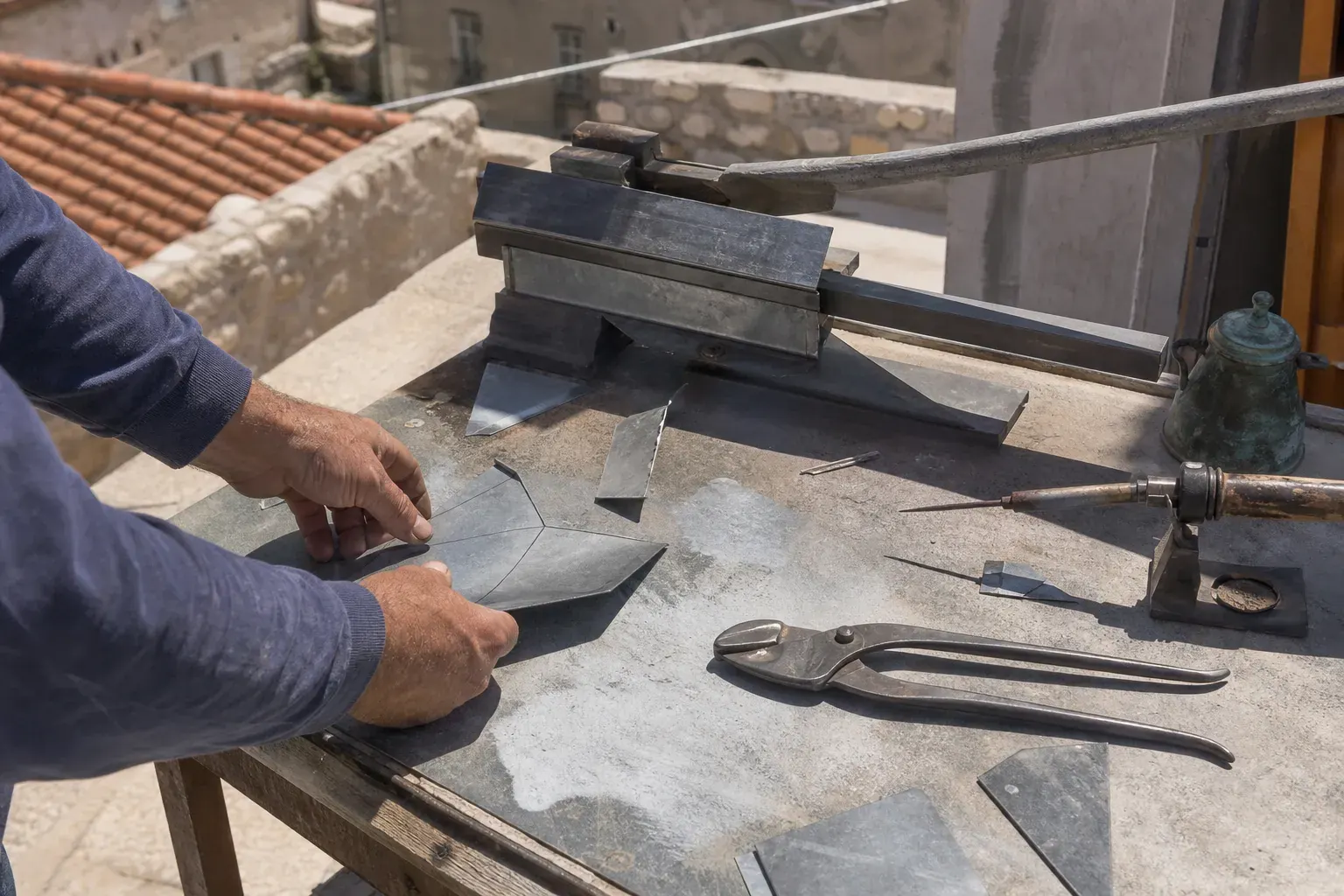Établi de zingueur en atelier, plieuse à main, pince à sertir, fer à souder sur son repose-fer et gabarit tracé