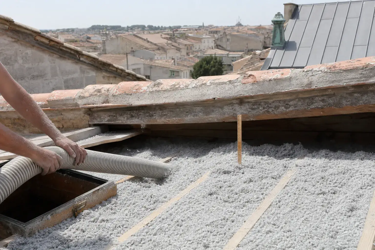 Isolant en vrac soufflé sur le plancher d’un comble perdu, couche régulière entre les solives et piquet de repère d’épaisseur