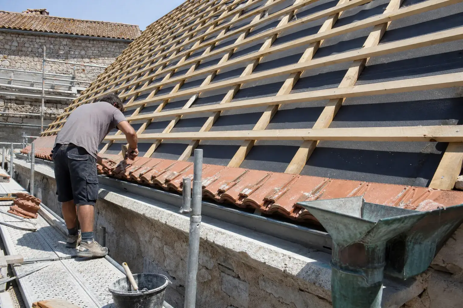 Versant en reconstruction vu depuis l’échafaudage, écran de sous-toiture tendu, contre-lattes et liteaux cloués en quadrillage